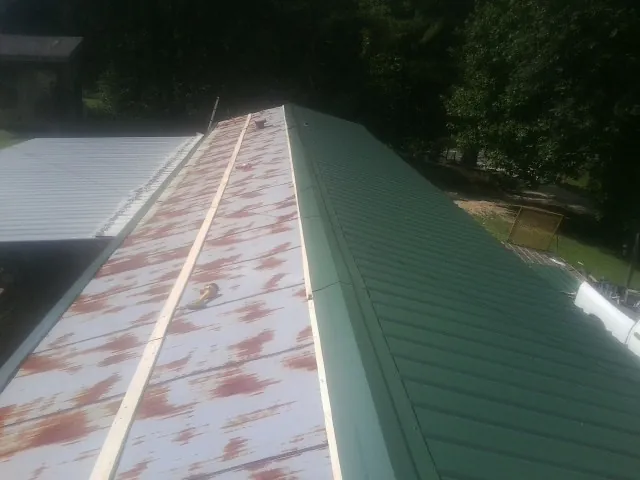 Old rusted panels beside newly installed green metal roofing — Wind Damage Roof Repair by Roofing Brothers in Pleasanton