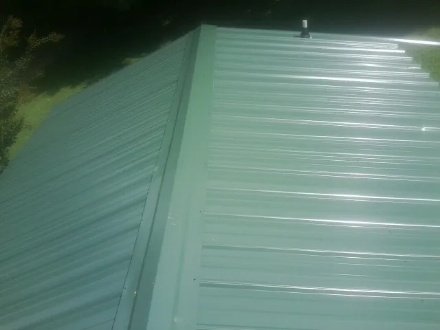 New green metal panels meeting at the ridge of a roof — Flat Roof Repair work by our crew in Pleasanton