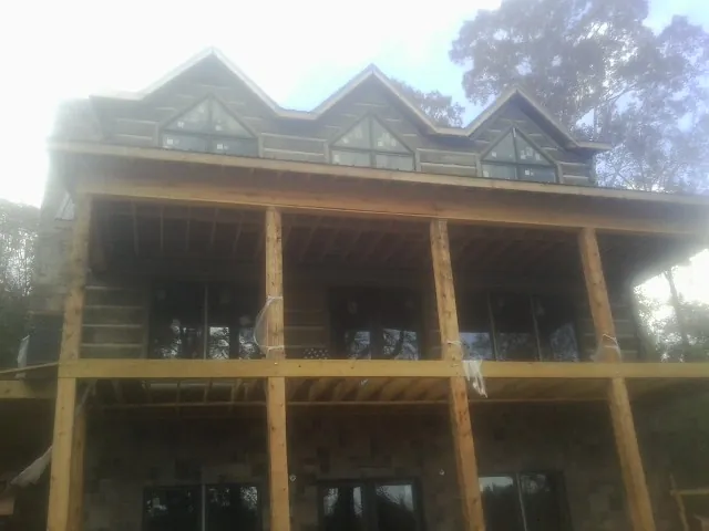 Dormers and porch framing on a large log home under construction — Roof Coating work by our crew in Pleasanton