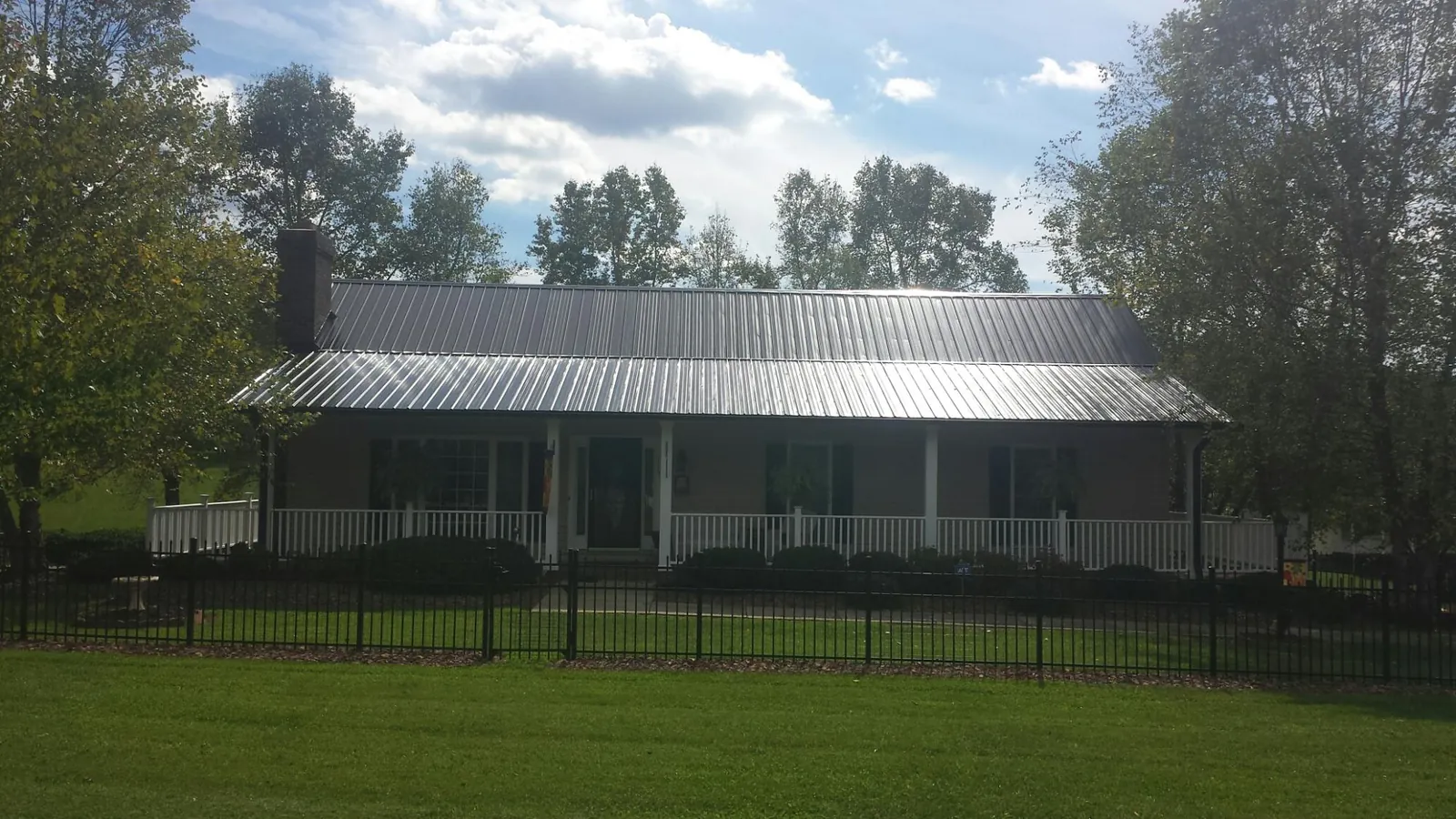 Gray metal roof on a brick ranch with a full width front porch — Gutter Guard Installation work by our crew in Pleasanton