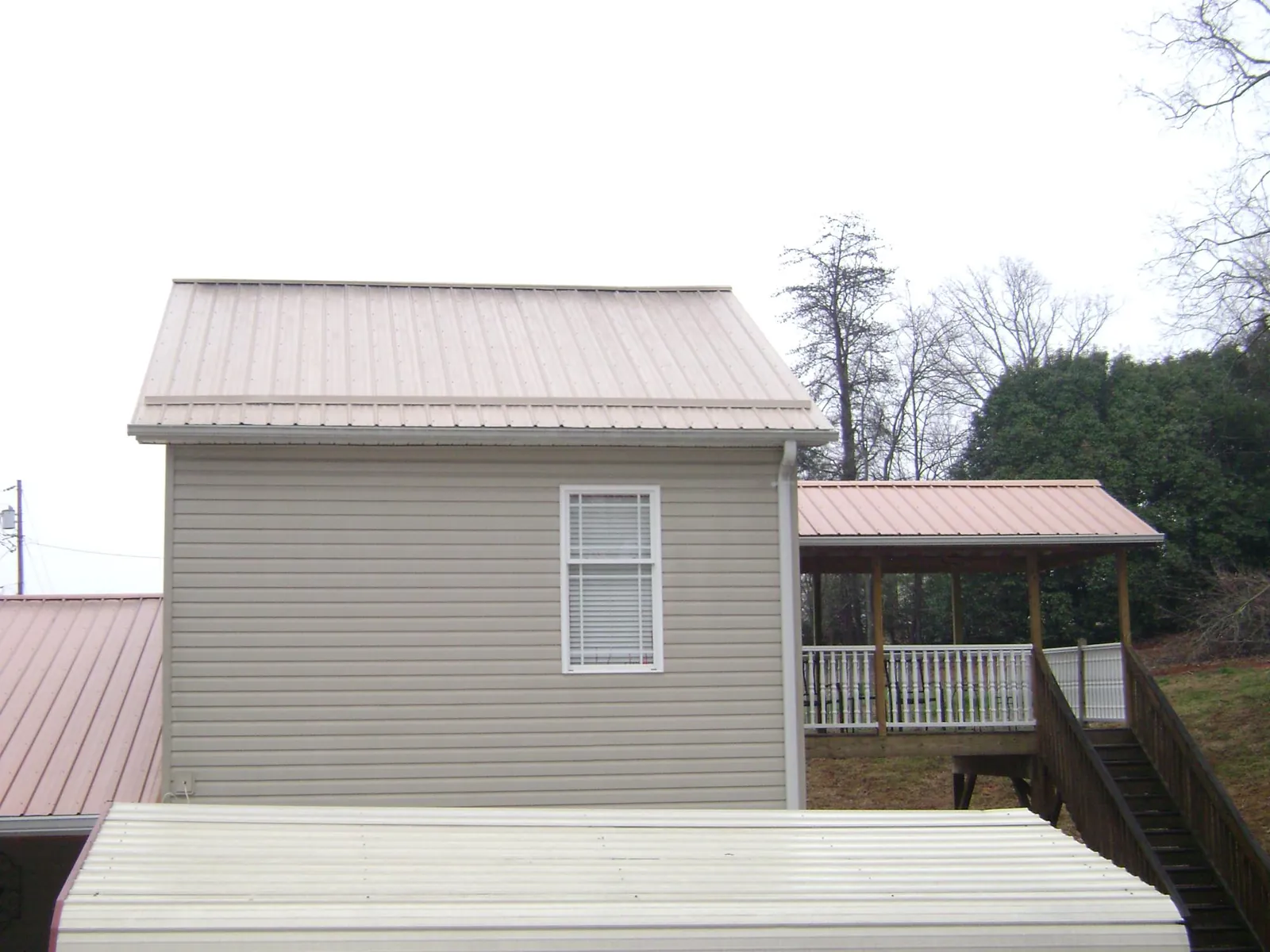 Tan metal roofs on a two story addition and attached porch, from a Roof Replacement job in Pleasanton